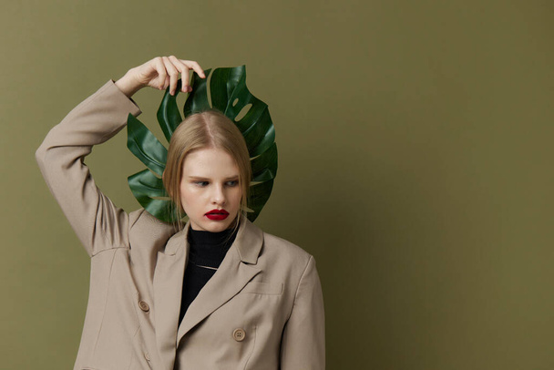 blondynka kobieta zielony liść palmy płaszcz jasny makijaż styl pozowanie - Zdjęcie, obraz