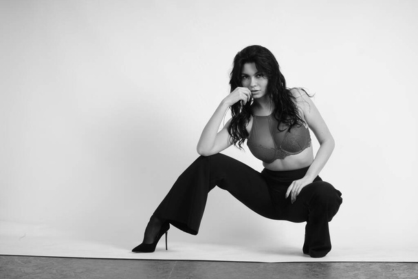 Schwarz-Weiß-Porträt einer schönen sexy Frau in schwarzer Kleidung, die im Studio posiert - Foto, Bild