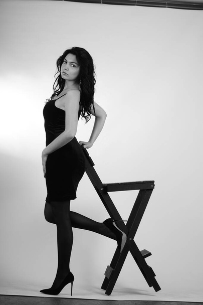 красивая молодая женщина в черном платье позирует в студии, черно-белая  - Фото, изображение