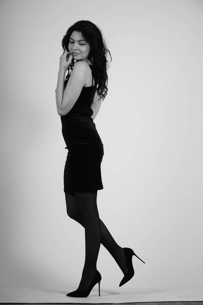 όμορφη νεαρή γυναίκα με μαύρο φόρεμα ποζάρουν σε στούντιο, μαύρο και άσπρο  - Φωτογραφία, εικόνα