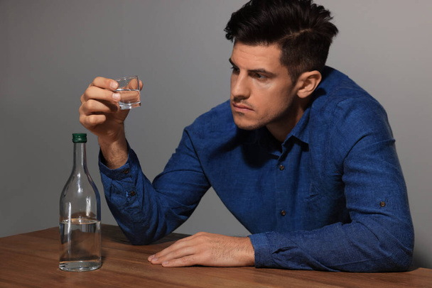 Addicted man with alcoholic drink at wooden table indoors - Photo, Image