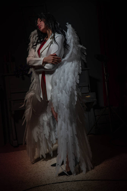 Όμορφο σέξι κορίτσι με κόκκινα εσώρουχα και λευκό σακάκι με φτερά που ποζάρουν στην κάμερα στο στούντιο  - Φωτογραφία, εικόνα