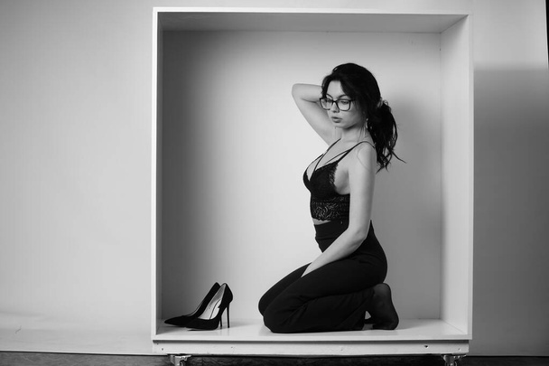 Siyah elbiseli güzel bir kadının siyah beyaz portresi stüdyoda poz veriyor. - Fotoğraf, Görsel
