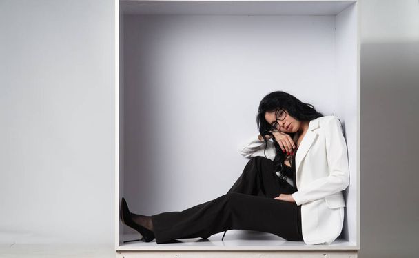 atractiva modelo morena joven sexy con top negro y chaqueta blanca posando en la cámara en la habitación blanca - Foto, imagen