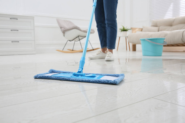 Woman cleaning parquet floor with mop at home, closeup - Fotó, kép