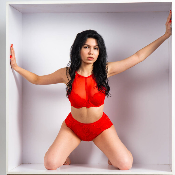 Hermosa chica sexy en lencería roja posando en la cámara en la habitación blanca - Foto, Imagen
