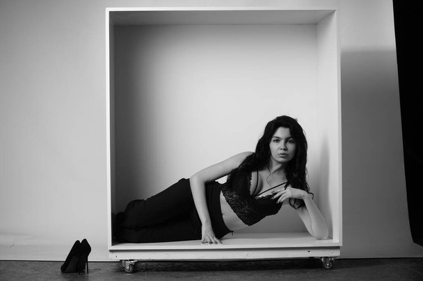 Siyah elbiseli güzel bir kadının siyah beyaz portresi stüdyoda poz veriyor. - Fotoğraf, Görsel
