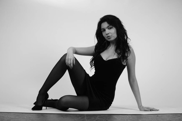 ασπρόμαυρο πορτραίτο μιας όμορφης σέξι γυναίκας με μαύρα ρούχα που ποζάρει στο στούντιο - Φωτογραφία, εικόνα