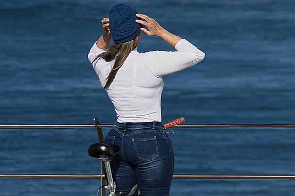 Γυναίκα με μπλε καπέλο δίπλα στον ωκεανό με ποδήλατο - Φωτογραφία, εικόνα