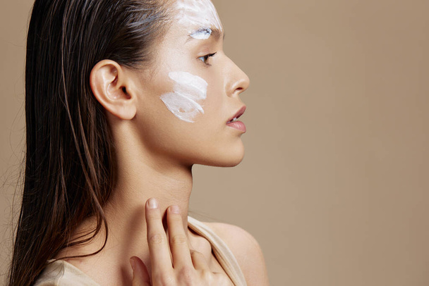 портрет жінки догляд за шкірою за допомогою білої маски на обличчі бежевий фон
 - Фото, зображення