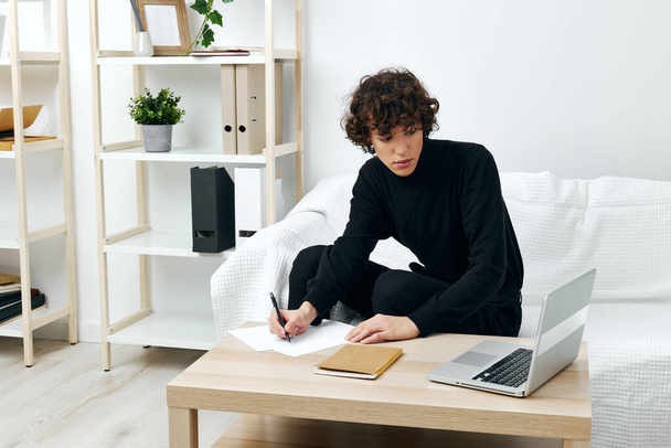 tipo sentado en la mesa en un suéter negro lecciones de comunicación - Foto, imagen
