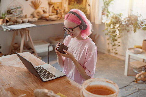 Young craftswoman with laptop computer in art studio - 写真・画像