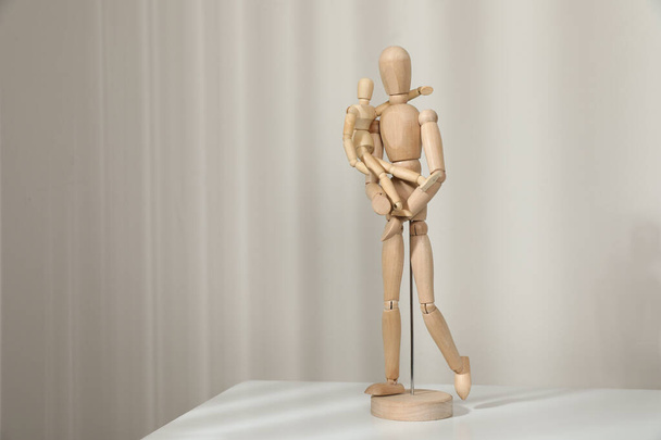 Wooden mannequins of parent with child on white table against light background, space for text. Family Day - Foto, Bild