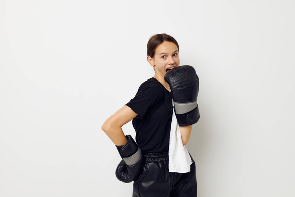athletic woman in boxing gloves in black pants and a T-shirt isolated background - 写真・画像