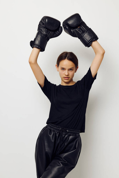 athletic woman in boxing gloves in black pants and a T-shirt isolated background - Foto, Imagem