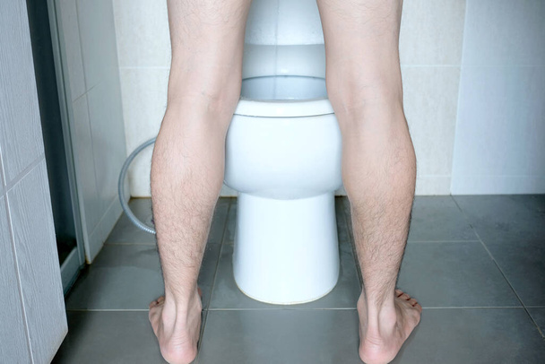 Dikiz ayağında evdeki tuvalette tuvalete işeyen bir adam var. Sağlık kavramı - Fotoğraf, Görsel