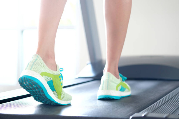 ランニングシューズで運動をするジムでトレッドミルを走る女性の足。健康とスポーツの概念の背景, - 写真・画像