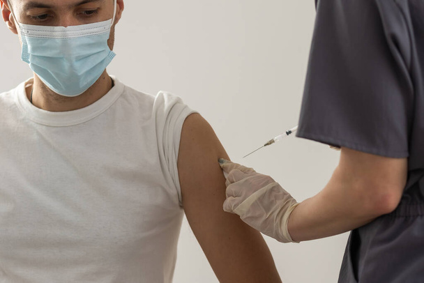 L'injection du vaccin COVID-19, le médecin en gants tient la seringue et fait du jab à la patiente en clinique. Prévention du coronavirus ou de la grippe. virus corona et vaccin antigrippal, thérapie et traitement - Photo, image