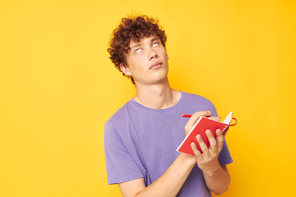 portrait of a young curly man notepad with pen learning emotions isolated background unaltered - Photo, Image