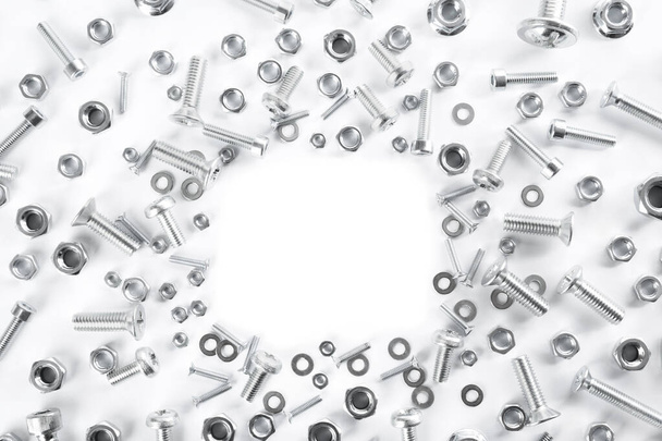 Frame of different metal bolts and nuts on white background, top view. Space for text - Zdjęcie, obraz