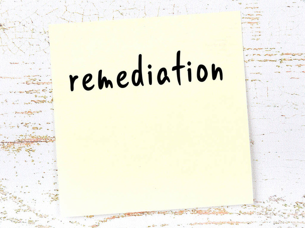 Concepto de recordatorio sobre la remediación. Hoja adhesiva amarilla de papel sobre pared de madera con inscripción - Foto, imagen
