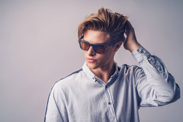 Мужская прическа концепция. Красивый мужчина со стильной стрижкой в солнечных очках на белом фоне - Фото, изображение