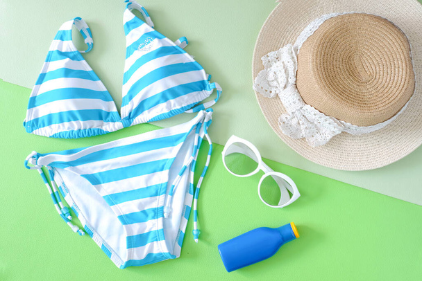 Nyári kiegészítők és kék fürdőruha bikini, Napszemüveg és kalap utazás a strandon. Rózsaszín pasztell színes háttér. Divat- és turisztikai koncepció - Fotó, kép