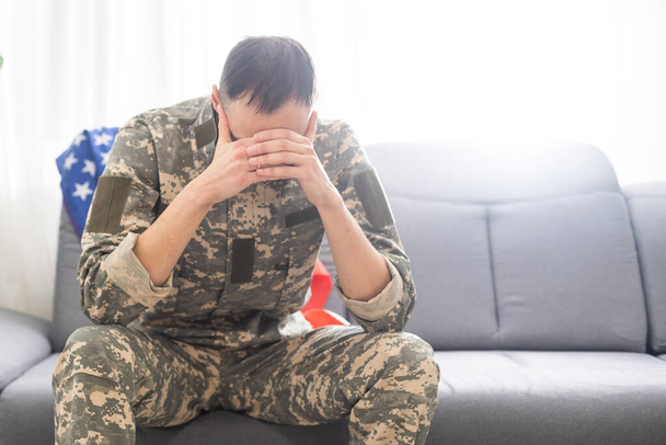 trieste soldaat in camouflage uniform houdt militaire tag in gebalde handen. - Foto, afbeelding