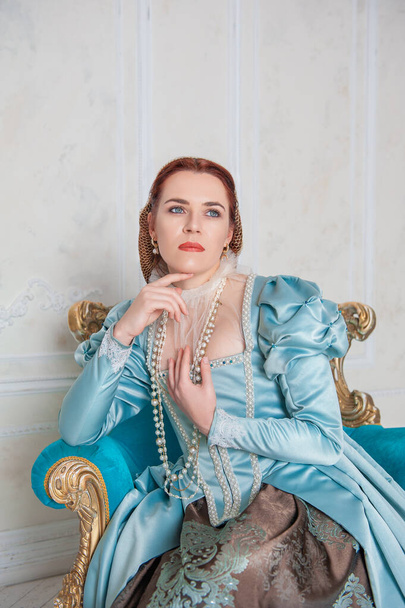 Hermosa mujer joven de estilo medieval vestido azul sentado en el armchai - Foto, imagen
