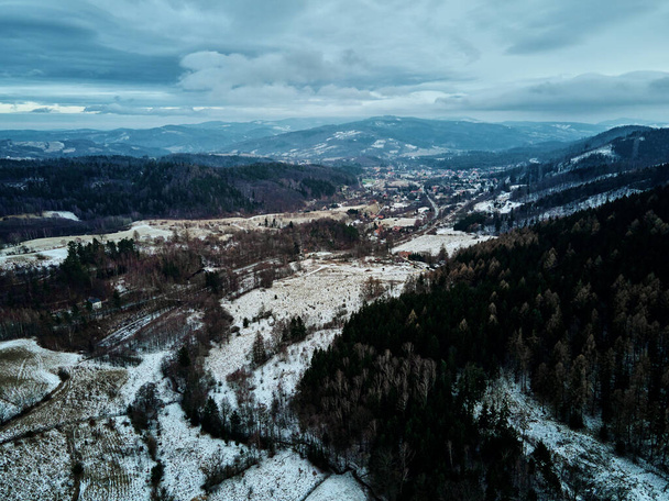 Kręta droga przez góry pokryte lasem, zimowy krajobraz z zakrzywioną autostradą wśród wsi, widok z powietrza - Zdjęcie, obraz