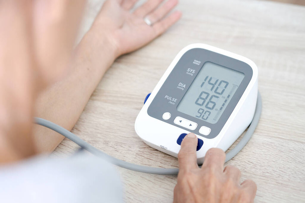 De mens controleert de bloeddrukmeter en de hartslagmeter met digitale manometer. Gezondheidszorg en medisch concept - Foto, afbeelding