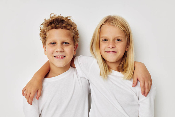 Portrait of cute children in white T-shirts are standing next to beige background - Foto, Imagen