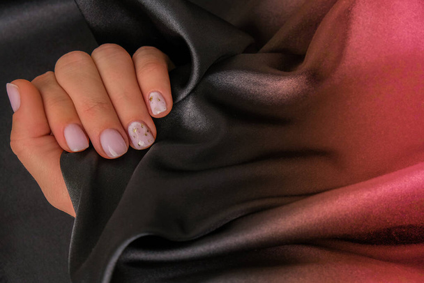 Close-up elegante pastel natuurlijke moderne design manicure op stof zijde achtergrond. Vrouwelijke handen. Gel nagels. Naakt manicure. Beige kleur. Schone huid. Kuuroord, reclame. Huidverzorging. Prachtig. Nagelverzorging. Schoonheidsbehandeling. Kopieerruimte - Foto, afbeelding
