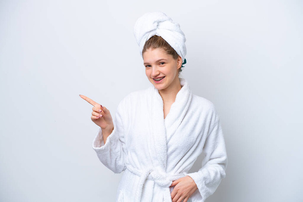Teenager Russian girl in a bathrobe isolated on white background pointing finger to the side and presenting a product - Valokuva, kuva