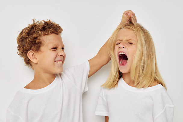 Boy and girl in white T-shirts are standing next to isolated background - Photo, Image