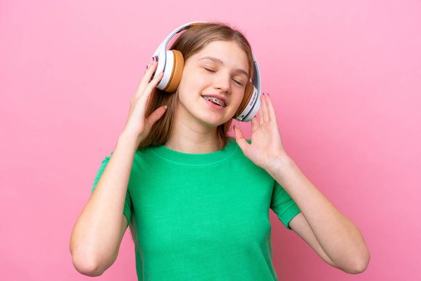 Teenager russische Mädchen isoliert auf rosa Hintergrund Musik hören und singen - Foto, Bild