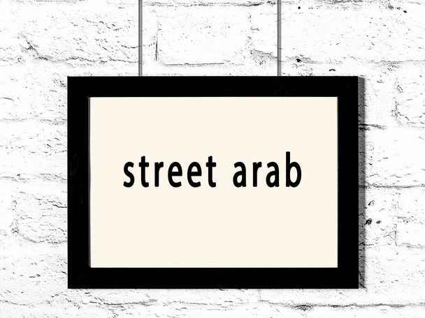Černý dřevěný rám s nápisem ulice arabsky visí na bílé cihlové zdi  - Fotografie, Obrázek