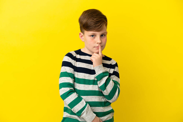 Little redhead boy isolated on yellow background having doubts while looking up - Fotó, kép
