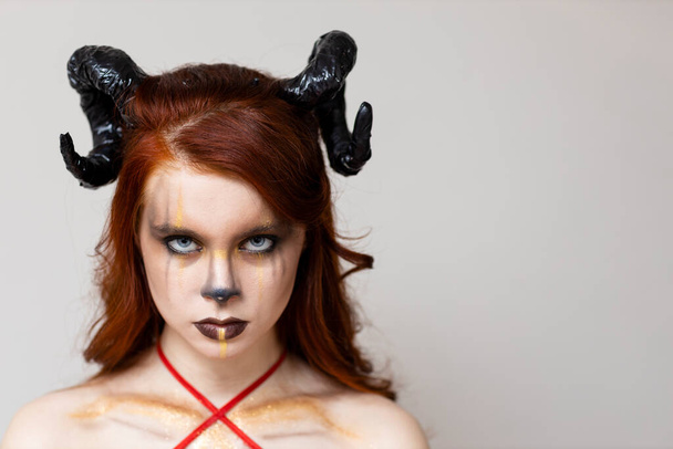 Όμορφη νεαρή γυναίκα με zodiac μακιγιάζ σημάδια του Αιγόκερω ή Κριός ή Ταύρος. Κορίτσι με κέρατα στο κεφάλι - Φωτογραφία, εικόνα
