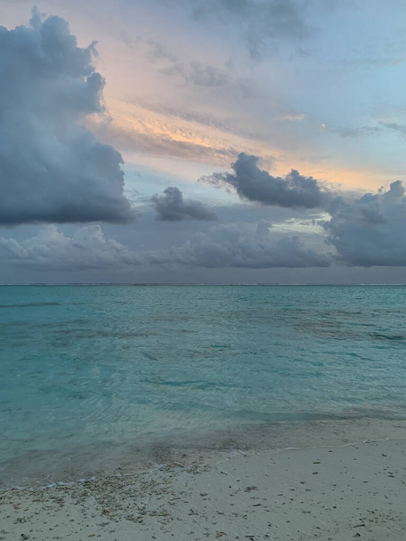 Malediiveja. Ilta Malediiveilla, näkymä huviloihin vedessä ja Intian valtameren rannikolla valkoisella hiekalla ja trooppisilla puilla kauniin taivaan taustalla pilvillä. - Valokuva, kuva