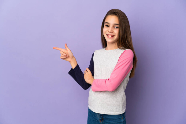 Little girl isolated on purple background pointing finger to the side - Фото, зображення