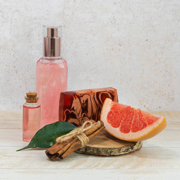 Grapefruit pieces, pink shower gel, essential oil and cinnamon. The concept of natural cosmetics. - Photo, Image