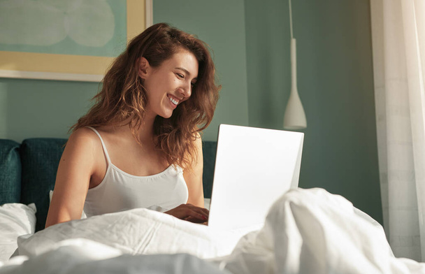 Happy woman using laptop in bed - Φωτογραφία, εικόνα
