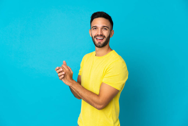 Young caucasian man isolated on blue background applauding - Foto, imagen