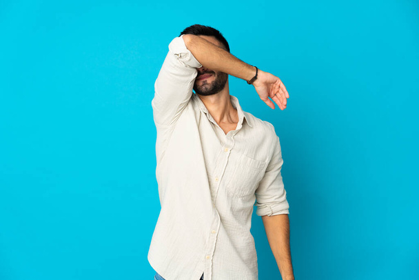 Young caucasian man isolated on blue background covering eyes by hands - Photo, Image