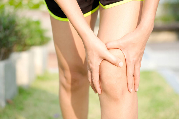 Knee pain .Woman stand on grass Her hand caught at the knee. Having painful feet and stretching muscles fatigue To relieve pain. health concepts. - Photo, image