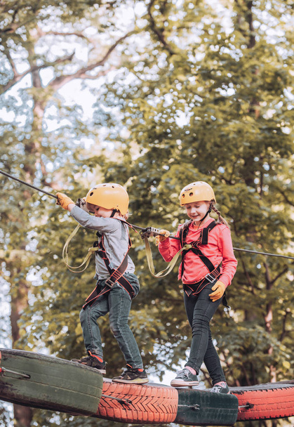 Safe Climbing extreme sport with helmet. Rope park. Cargo net climbing and hanging log. Cute school child boy enjoying a sunny day in a climbing adventure activity park. - Foto, Imagem