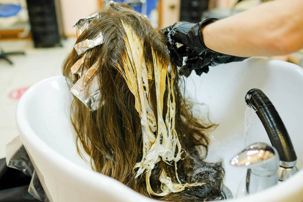 Мытье головы после выделения нитей. Девушка в салоне. - Фото, изображение
