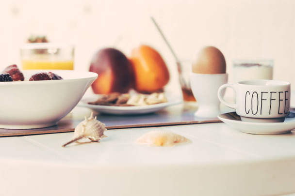 Frühstückstisch gefüllt mit verschiedenen Speisen, herzhaften, süßen, heißen und kalten Getränken. Weißer Frühstückstisch auf der Terrasse. Trinken, Essen und Lifestyle-Konzept. - Foto, Bild