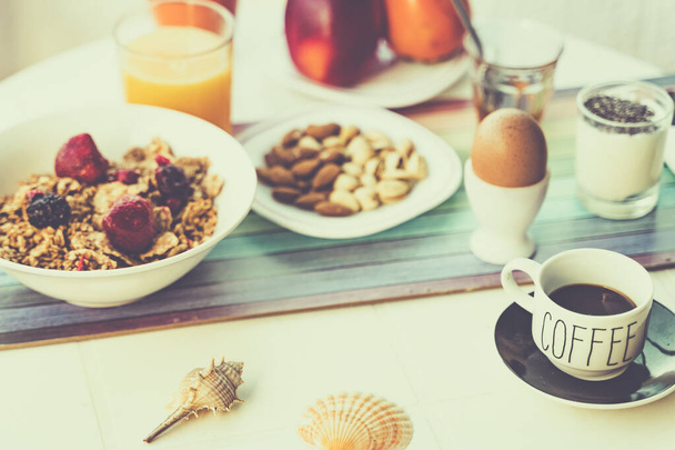 Frühstückstisch gefüllt mit verschiedenen Speisen, herzhaften, süßen, heißen und kalten Getränken. Weißer Frühstückstisch auf der Terrasse. Trinken, Essen und Lifestyle-Konzept. - Foto, Bild